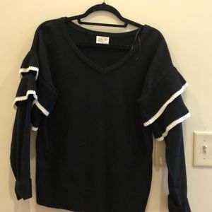 black sweater with white contrast ruffle sleeves